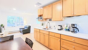A modern kitchen with wooden cabinets, a microwave, a coffee maker, and a sink. - Ocean Park B&B (Surrey)