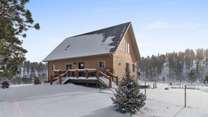Une cabane en bois dotée d’un porche abrité et surplombant un paysage enneigé.