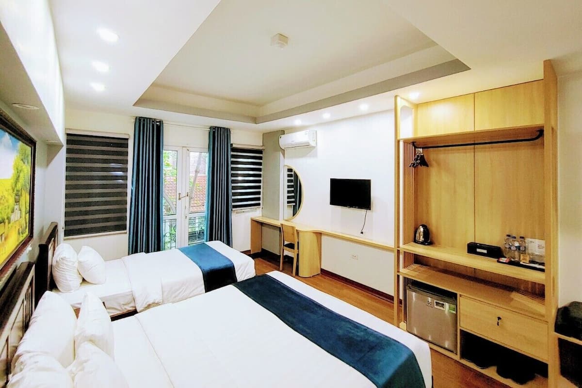 Une chambre d’hôtel avec deux lits, un bureau, une télévision et une armoire.