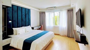 Una habitación de hotel moderna con una cama grande, un televisor de pantalla plana y un armario empotrado.