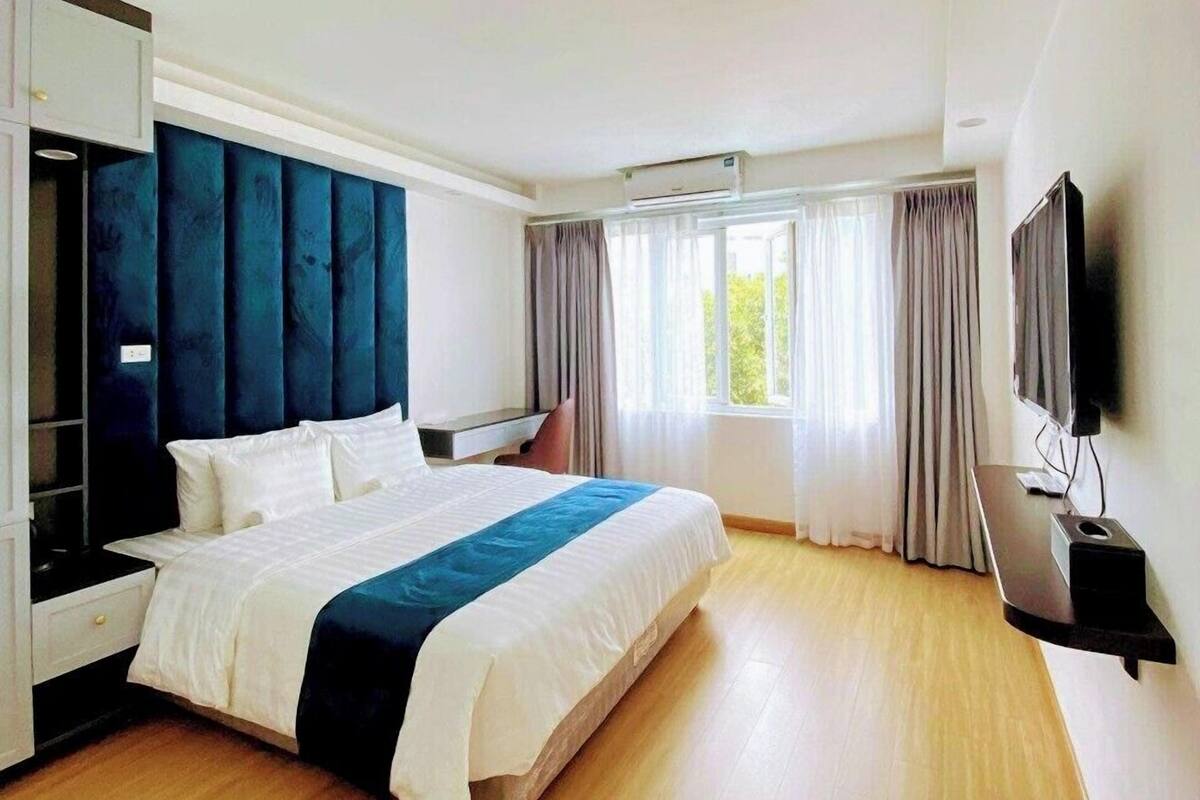 Une chambre d’hôtel moderne dotée d’un grand lit, d’un téléviseur à écran plat et d’une armoire intégrée.