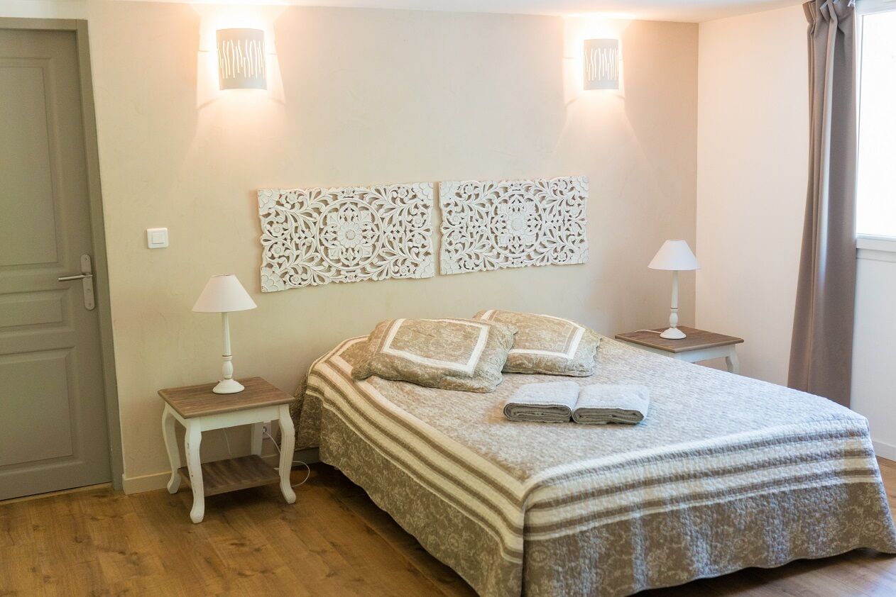 A bedroom with a bed, two nightstands, a door, and decorative wall art.