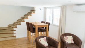 Een eetgedeelte met een houten tafel en stoelen, een trap en een raam met gordijnen.