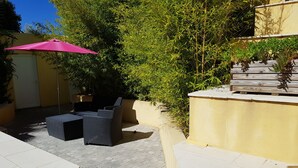 Een terras met zitgedeelte en een roze parasol.
