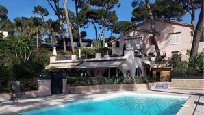 A swimming pool with a tiled deck, surrounded by a building with a terracotta roof and arched windows. - Cap D'Antibes sea, swimming pool, 2 large terraces, nature and pines (Antibes)