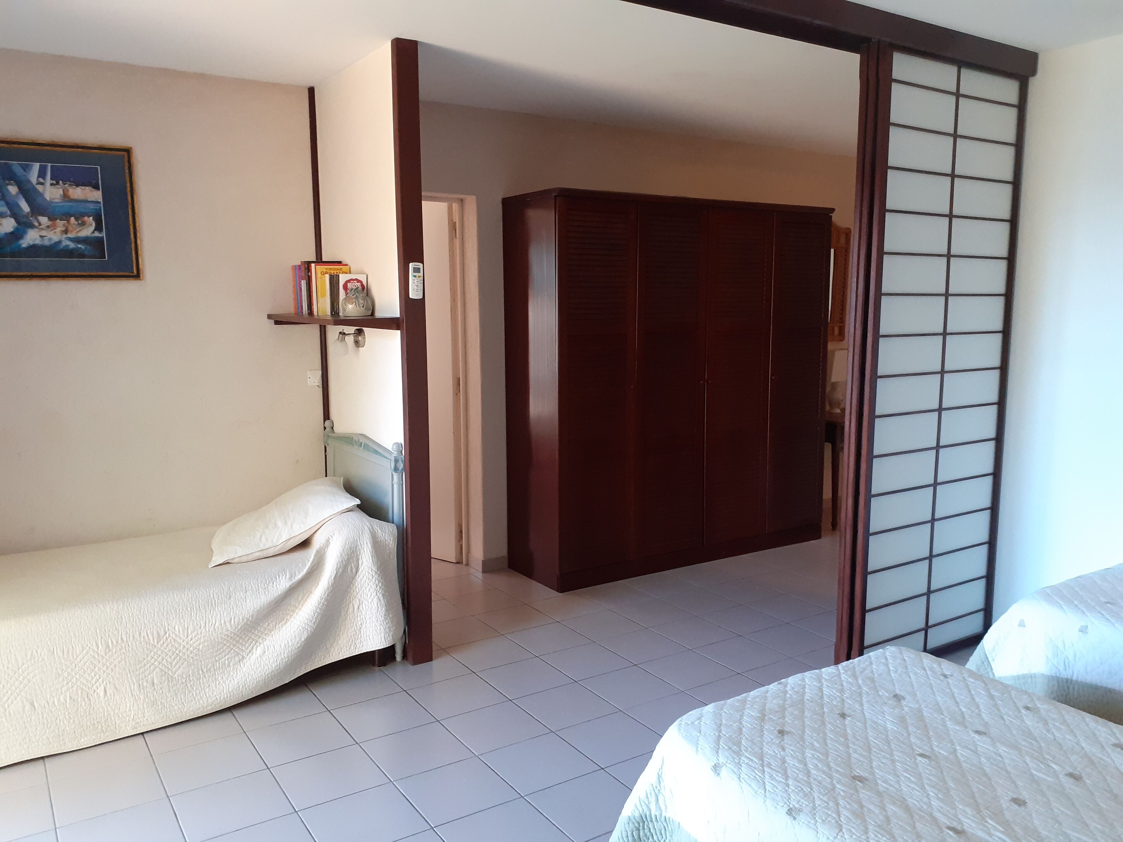 Une pièce comprenant un lit, un petit canapé, une armoire en bois et une porte coulissante.