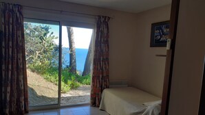 Una habitación con una cama, vista al mar y una puerta que da al exterior.