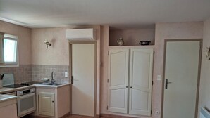 Una cocina compacta con estufa, lavamanos y un armario de dos puertas.