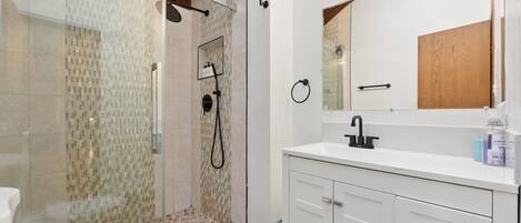 A modern bathroom with a glass-enclosed shower, a white sink, and a wooden cabinet.