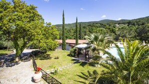 Une villa avec piscine, entourée d’une végétation luxuriante et de collines.