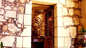 Entrada de un edificio de piedra con piso de baldosas y una planta en maceta.