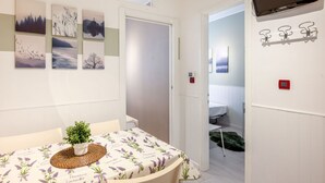 Huoneessa on ruokapöytä, ruukkukasvi ja seinälle asennettu televisio.
