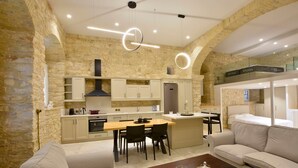 Una cocina moderna con paredes de piedra, un comedor con mesa y sillas de madera, y una sala de estar con sofá y mesa de centro.