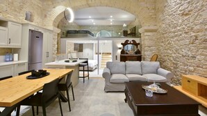 Un espacio habitable compacto con cocina, comedor y zona de estar, con paredes de piedra y mobiliario moderno.