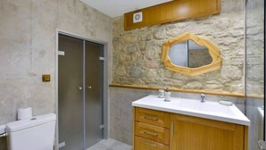 Un baño con pared de piedra, tocador de madera, espejo y retrete.
