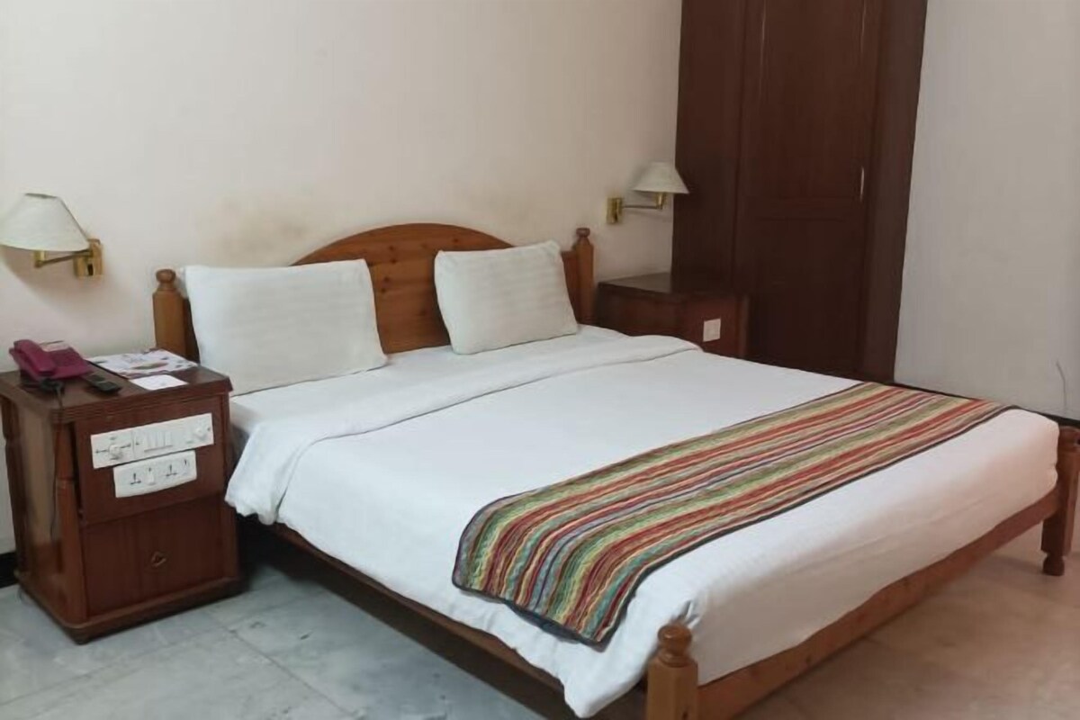 A neatly made bed with a striped blanket, a wooden headboard, and two bedside lamps.