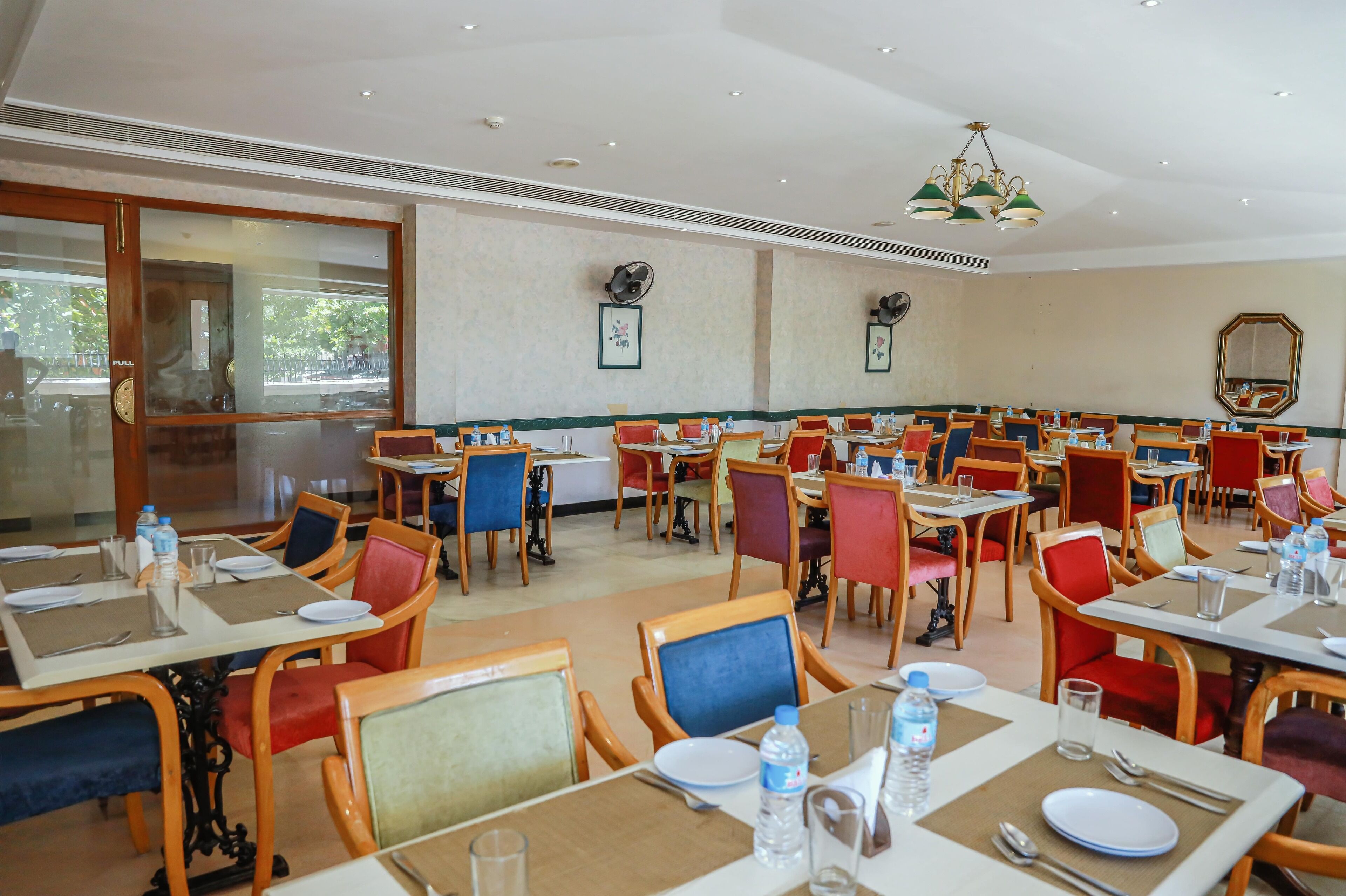 A dining area with multiple tables and chairs, each set with plates, cutlery, and water bottles.
