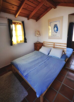 A bedroom with a wooden bed frame, a nightstand, a lamp, and a framed picture on the wall. - The perfect blend of tranquillity, beauty and functionality. (Chio)