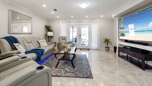 A modern living room with a leather sofa, a coffee table, and a flat-screen TV. - MerSea Beaucoup @ Gulf Highlands Sleeps 6 (Panama City Beach)