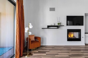 A modern living room with a fireplace, a sofa, and a floor lamp. - Stylish Palm Springs Retreat with Pool (Palm Springs)