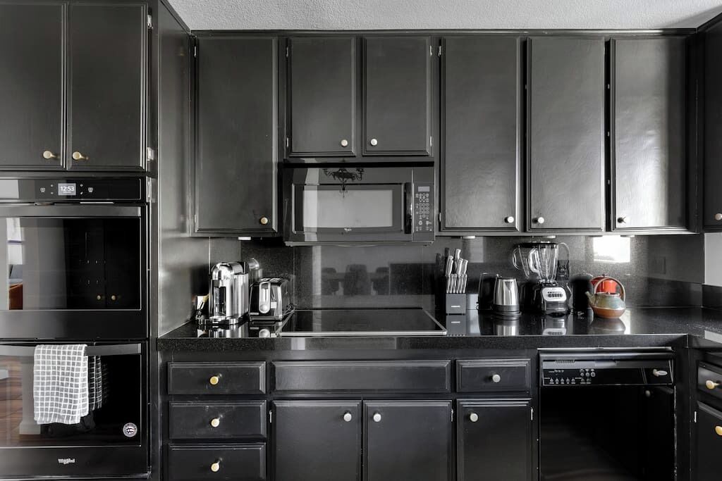 A modern kitchen with dark cabinetry, stainless steel appliances, and a central island.