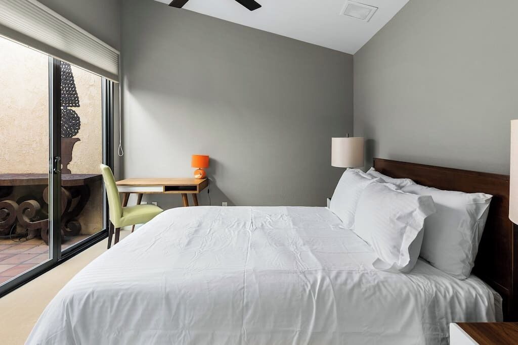 A hotel room with a bed, a desk, a chair, and a window.