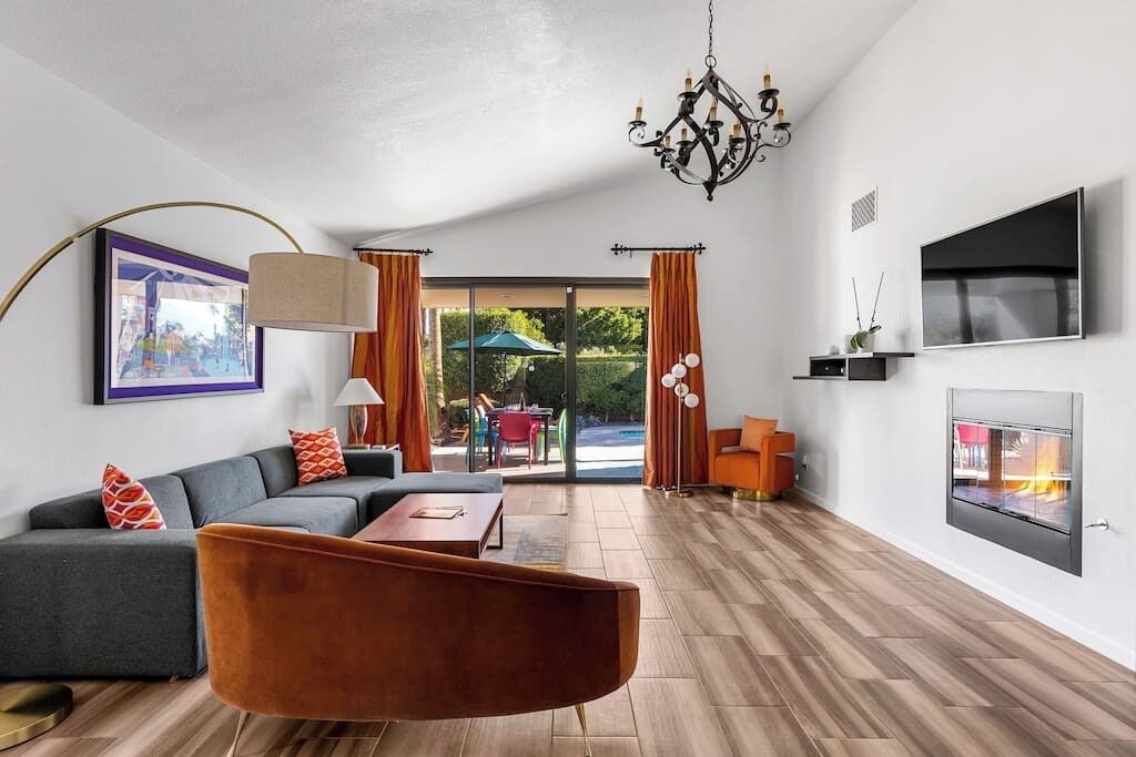 Een moderne woonkamer met een hoekbank, salontafel, open haard en een aan de muur bevestigde televisie.