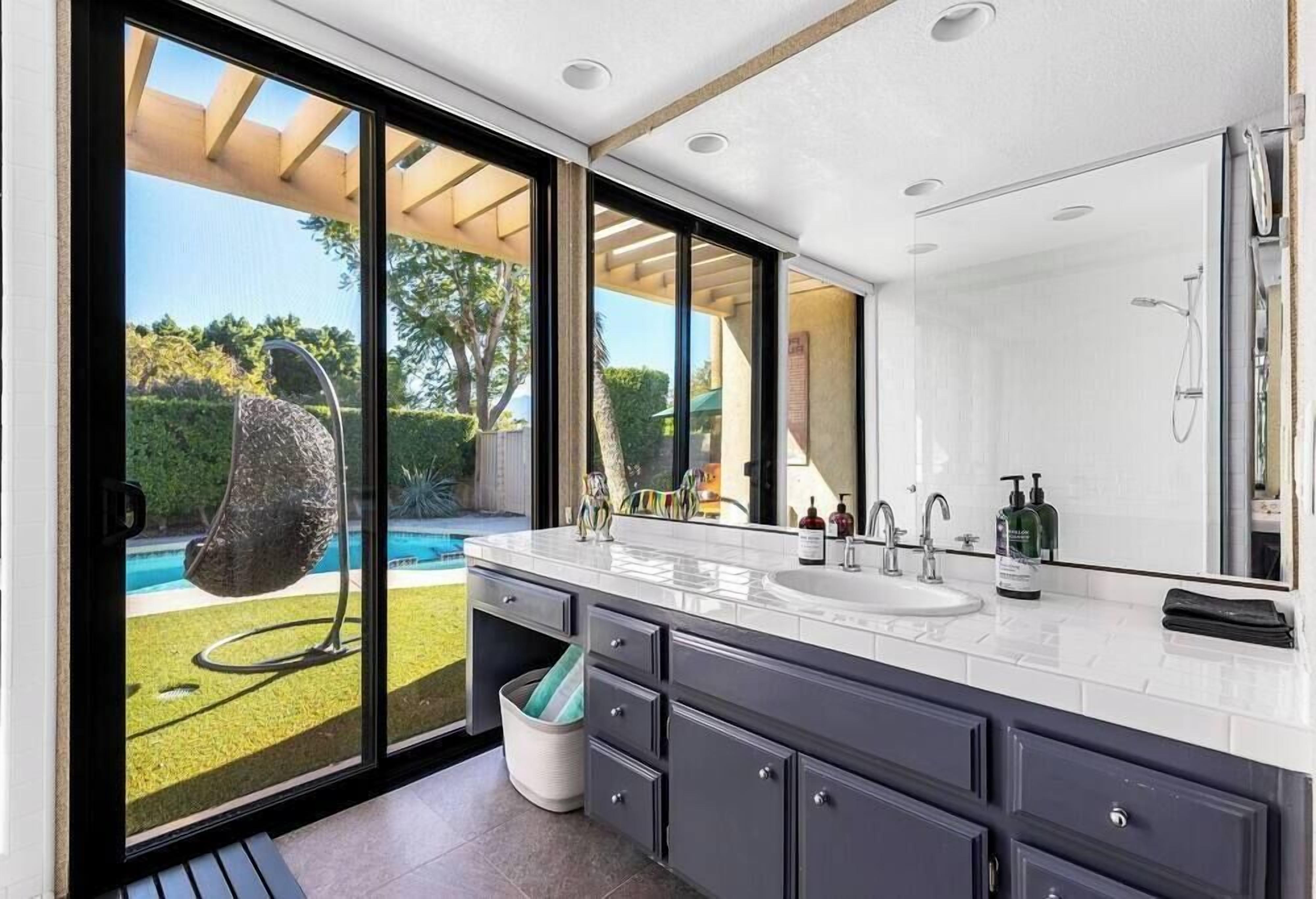 A modern bathroom with a large window, a built-in sink, and a shower.