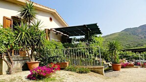 A building with a sloped roof, surrounded by potted plants and a gravel driveway. - 2-Room apartment with terrace overlooking the sea, private parking (Rio)