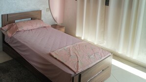 A bedroom with a bed, a nightstand, a wooden dresser, and a window with curtains. - Boujemaa's house 2 (Tanger)