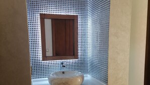 A bathroom with a white sink, wooden cabinet, and a mirror above it. The walls are tiled with a blue pattern. - Boujemaa's house 2 (Tanger)