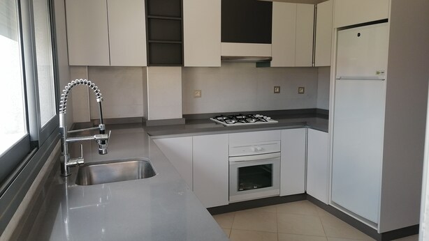 A modern kitchen with white cabinets, a stainless steel sink, a gas stove, and a built-in oven. - Boujemaa's house 2 (Tanger)