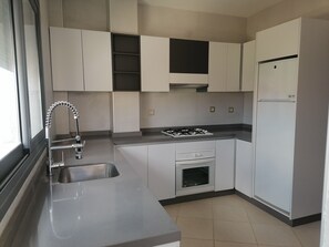 A modern kitchen with white cabinets, a stainless steel sink, a gas stove, and a built-in oven.