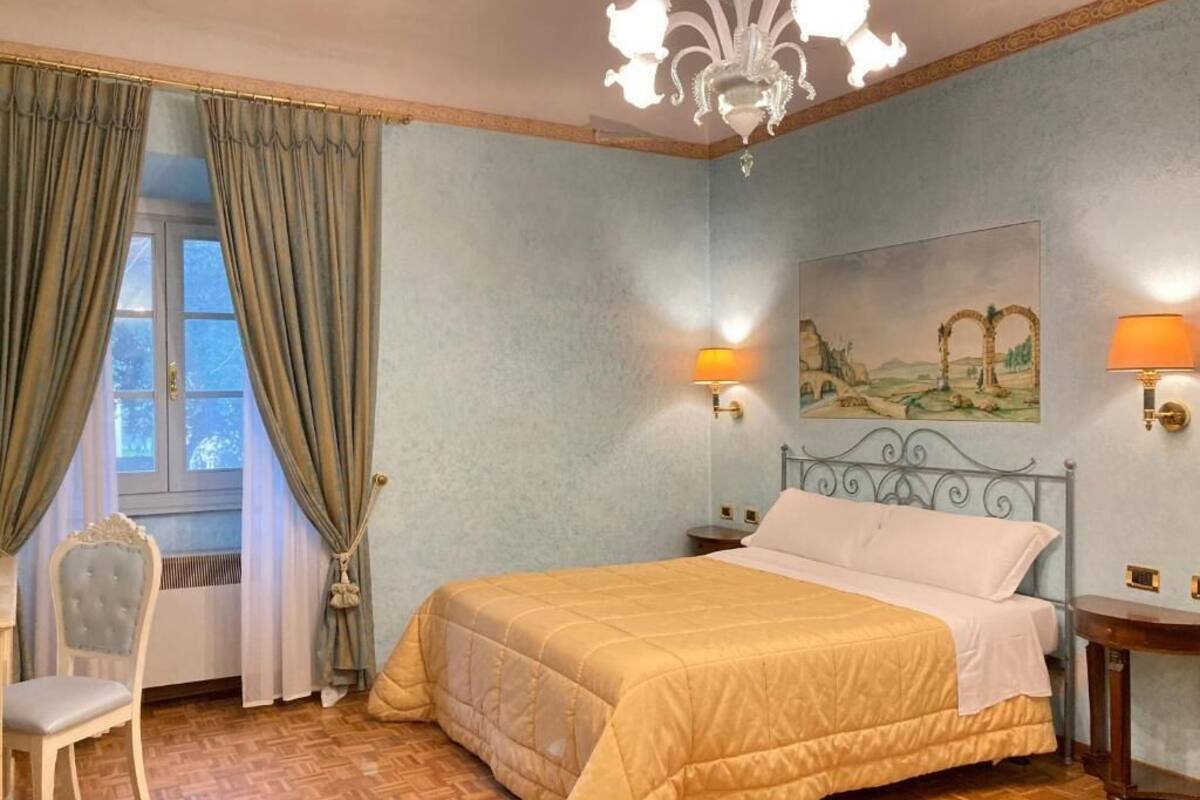 Ein Schlafzimmer mit Bett, einem Sessel, einem Bild an der Wand und einer Deckenleuchte.