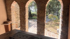 Un espacio interior con una pared de piedra, tres aberturas arqueadas y una mesa con un tablero de juego.