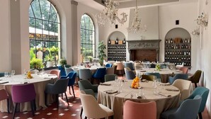 Un comedor con mesas redondas, sillas y candelabros.