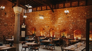 A restaurant with stone walls, wooden tables, and hanging lights. - Fibar Hotel Zincirlihan (Aydin)