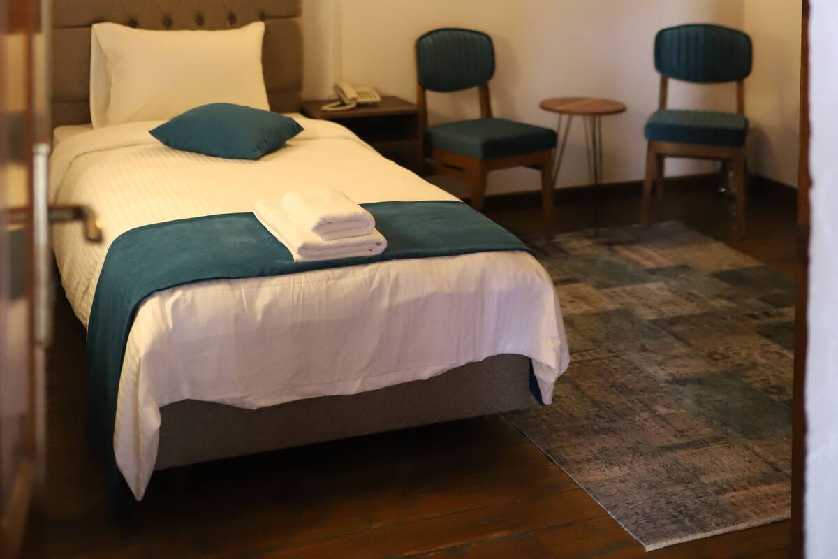 Ein Schlafzimmer mit einem Bett, zwei Stühlen, einem kleinen Tisch und einem Bild an der Wand.