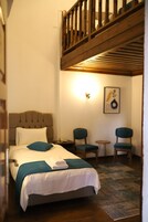 Un dormitorio con cama, dos sillas, una mesita y un cuadro en la pared.
