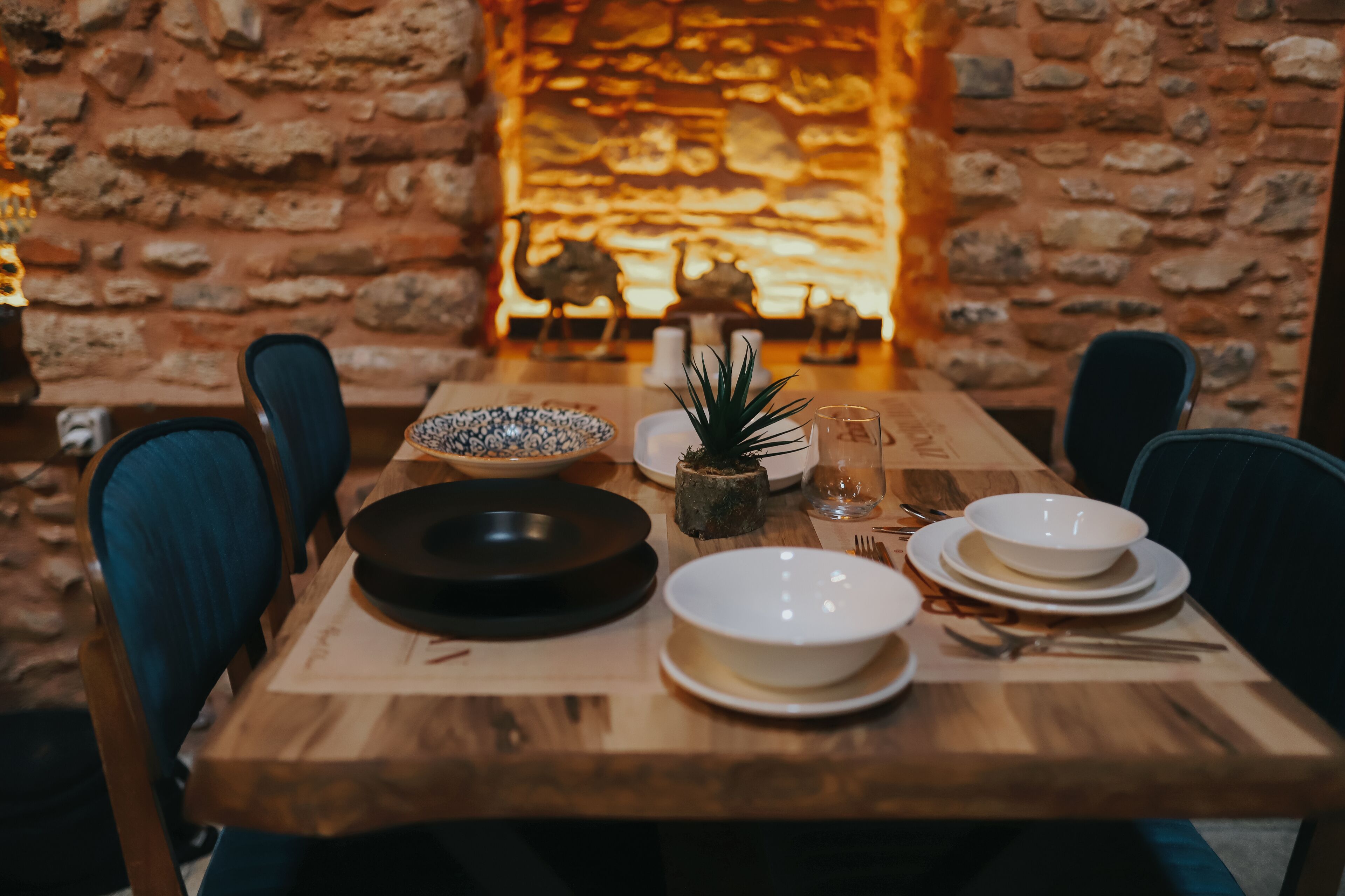 A wooden dining table set with plates, bowls, and cutlery, with chairs around it.