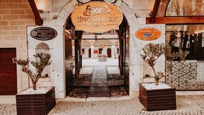 The entrance to Fibar Hotel Zincirlihan with a wooden sign, a pathway leading to the interior, and potted plants on either side. - Fibar Hotel Zincirlihan (Aydin)
