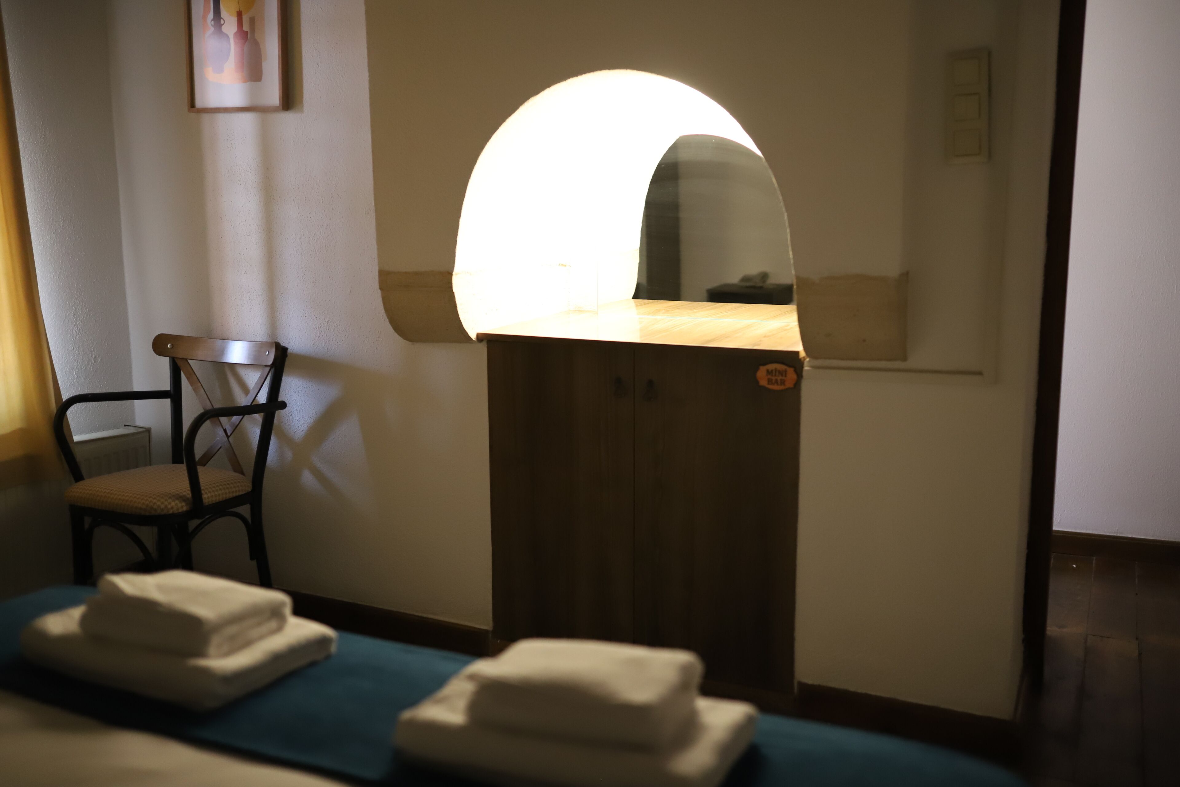 A room with a wooden cabinet, a chair, and a massage table with towels.