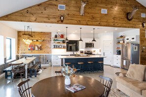 Een ruime keuken met moderne apparatuur, een eetgedeelte met houten meubels, en een woonkamer met een bank.