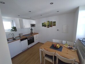 A compact kitchen with white cabinets, a microwave, a dishwasher, and a dining table with chairs.