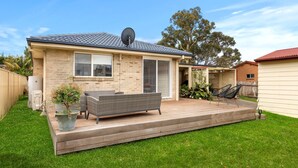 A house with a deck, a satellite dish, and a lawn.