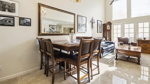 A dining area with a wooden table, chairs, a chandelier, and a large mirror.