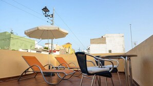 A rooftop terrace with two lounge chairs, a table, and an umbrella. - A cozy blend of tranquility, beauty and functionality (Chío)