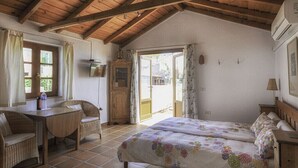 A cozy room with a bed, a desk, and a chair. There is a window and a door leading outside. - A cozy blend of tranquility, beauty and functionality (Chío)