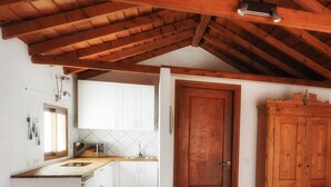 A kitchen with white cabinets, a wooden door, and a tiled floor. - A cozy blend of tranquility, beauty and functionality (Chío)