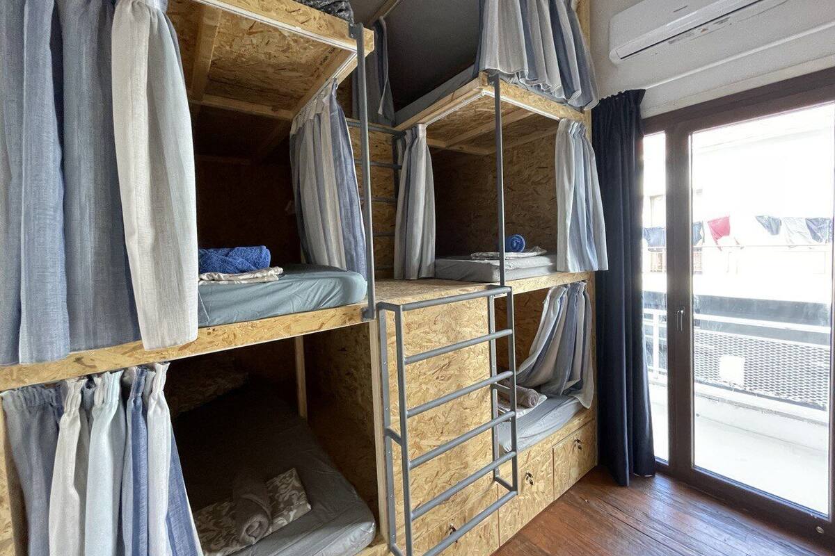 Une chambre avec un lit superposé, un plancher en bois, une échelle en métal et des rideaux.